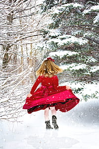 girl wearing red dress standing in front of snow covered trees thumbnail