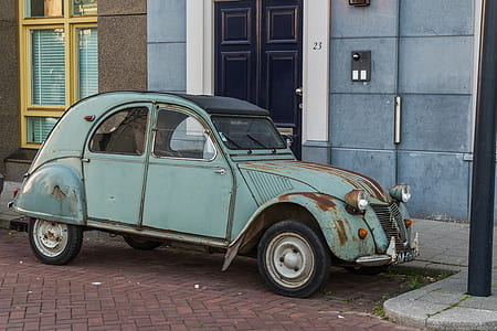 teal Volkswagen Type 1 parked beside blue and gray concrete building at daytime thumbnail
