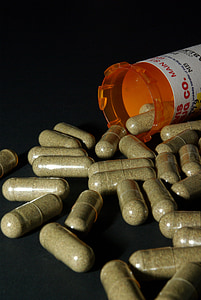 medication capsules spilling from orange prescription bottle on black surface thumbnail