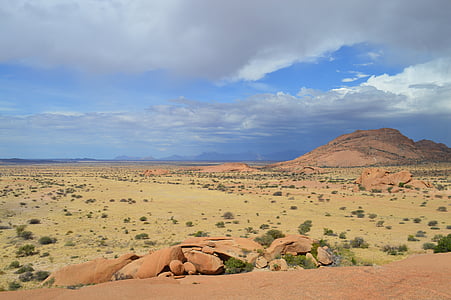 landscape photography of brown hill under cloudy sky thumbnail