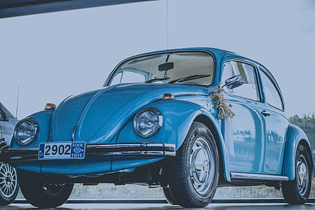 blue Volkswagen Beetle coupe beside black car thumbnail