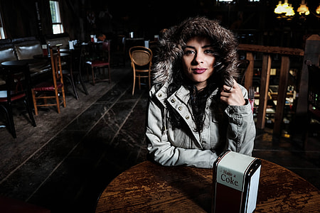 woman in gray parka jacket sitting on table thumbnail