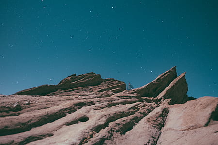 person on mountain below stars on sky thumbnail