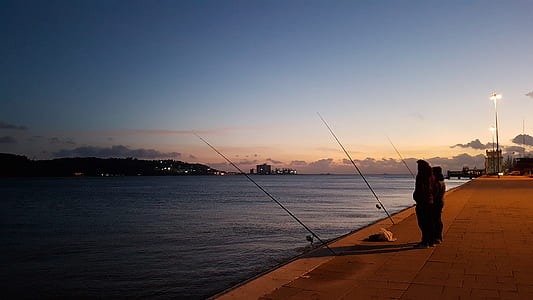person standing on bay beside fishing rod thumbnail