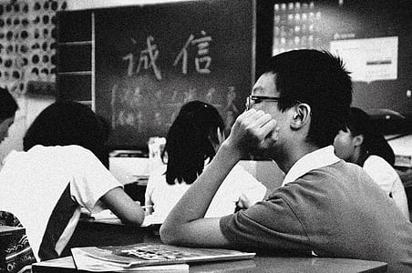 grayscale photo of boy inside classroom thumbnail