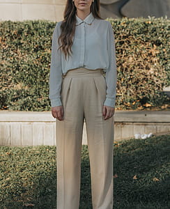 woman in white top and beige pants standing on green alwn thumbnail