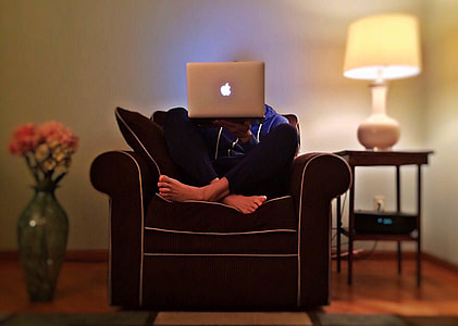 person holding MacBook while sitting on sofa chair thumbnail