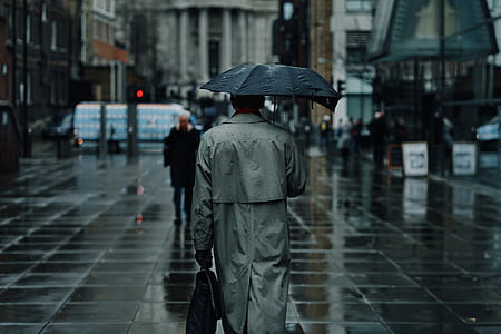 person under black umbrella walking in sidewalk thumbnail