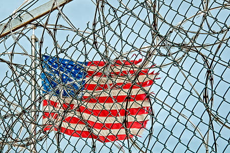 American flag beside gray wire link fence with live wire fence at daytime thumbnail