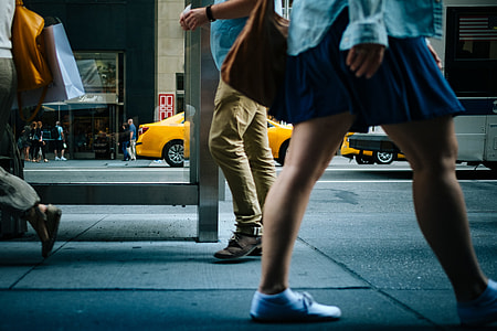 woman wearing white sneakers and blue skirt walking on sidewalk beside gray waiting shed at daytime thumbnail