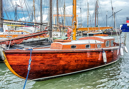 brown sailboat docked near grey boat thumbnail