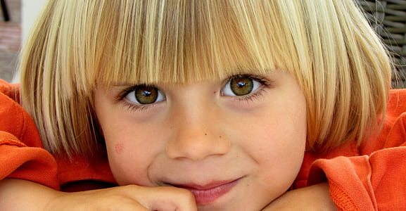 child with blonde hair wearing orange long-sleeved shirt thumbnail