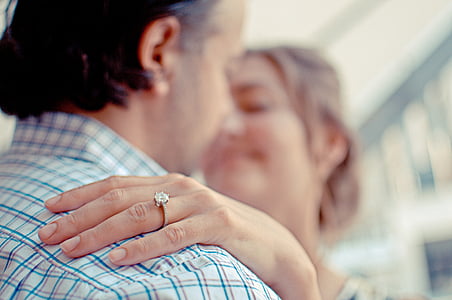 woman wearing silver-colored clear gemstone ring with her hands on man's shoulder thumbnail