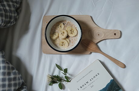 cooked banana inside ceramic bowl beside wood ladle on top of chopping board thumbnail