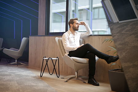 Young Adult Man sitting on office chair near the window of room and looking out thumbnail