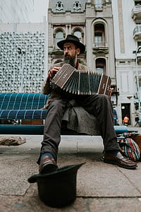 man sitting on blue bench playing accordion thumbnail