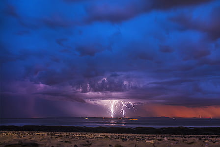 photo of clouds with lightning at sea at nighttime thumbnail
