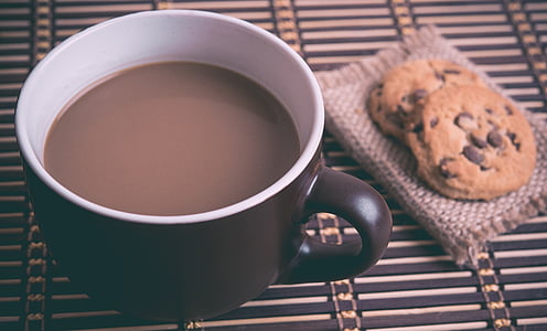 black and white ceramic mug filled with coffee beside cookies thumbnail
