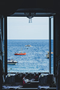 open window overlooking four boats on the sea during daytime photography thumbnail