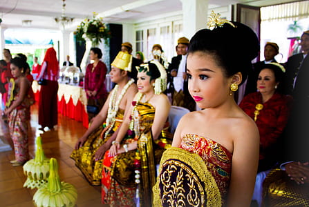 girl in traditional dress standing near couple indoors thumbnail