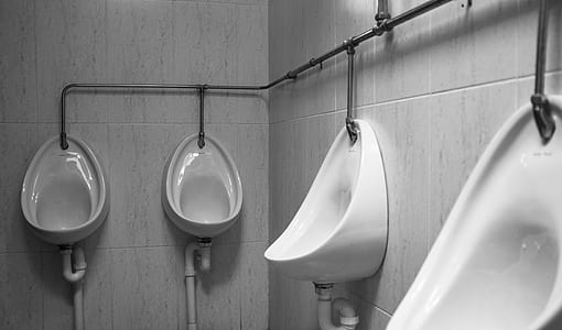 white ceramic urinals on wall thumbnail