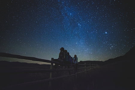 people sitting on fence looking up at nighttime thumbnail