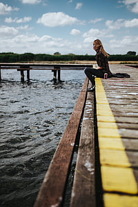 Beautiful blonde woman on a wooden pier by the lake thumbnail