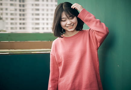 woman wearing red sweatshirt standing near green wall thumbnail