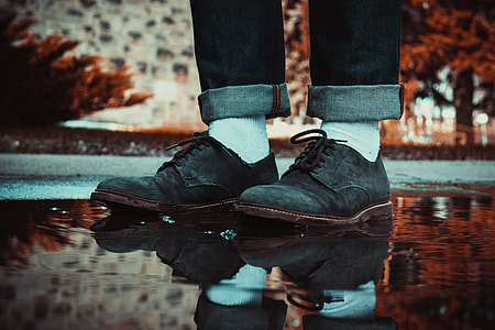 person wearing black suede mid-top shoes standing on puddle thumbnail