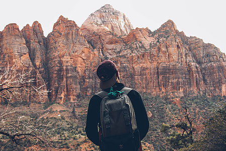 person wearing grey backpack standing near mountains thumbnail