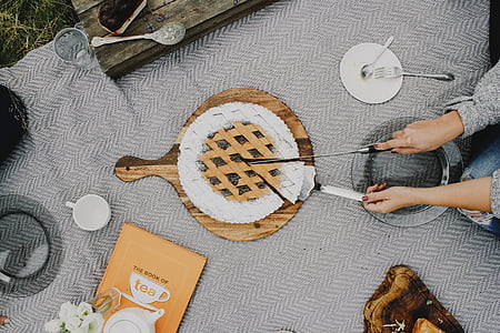 person putting pie on brown wooden pie server thumbnail