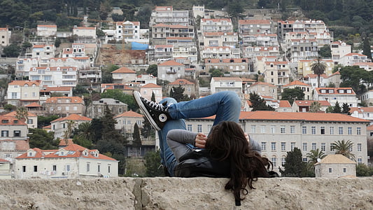 woman lying on brown concrete wall front of city building thumbnail