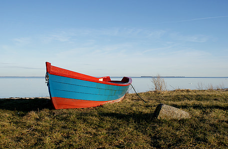 wooden boat on field of grass fronting sea thumbnail