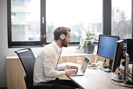 A young caucasian man in formals working on laptop while wearing headset thumbnail
