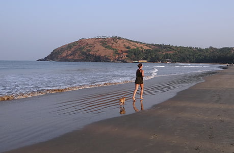 woman walking on shoreline with dog thumbnail