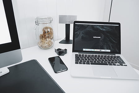 MacBook Pro is turned on beside iPhone on table thumbnail