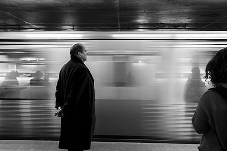 grayscale photography of man standing in front of passenger train thumbnail