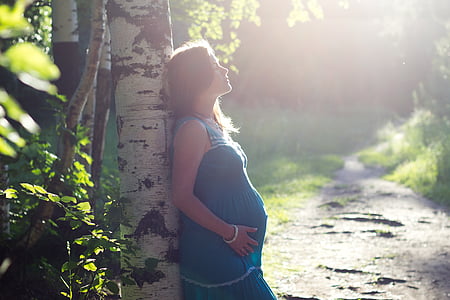 pregnant woman leaning on tree thumbnail