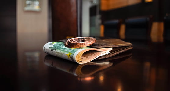 green banknote and bronze-colored coin on brown leather bifold wallet thumbnail