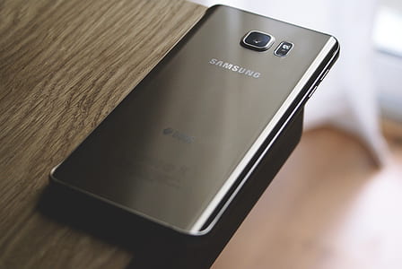 Silver Samsung Galaxy Smartphone on Top of Brown Wooden Table thumbnail