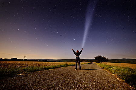 person on road raising hands near trees under gray sky thumbnail