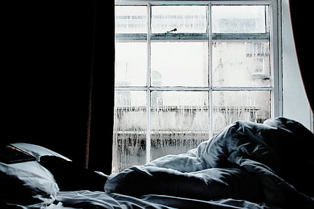 empty bed with crumpled duvet near window thumbnail