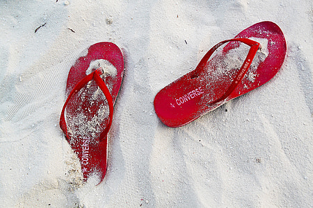 pair of red Converse flip-flops on sand thumbnail