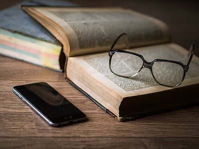 eyeglasses with black plastic frame on top of open book thumbnail