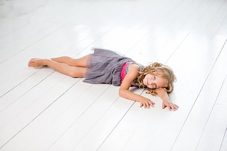girl in grey sleeveless dress lying on white floor thumbnail