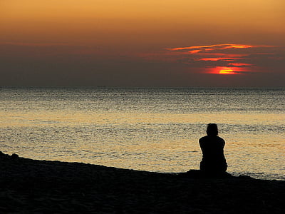 person sitting near seashore during golden hour thumbnail