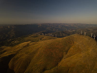 Aerial View of White Turbines on Green Grass Hills thumbnail