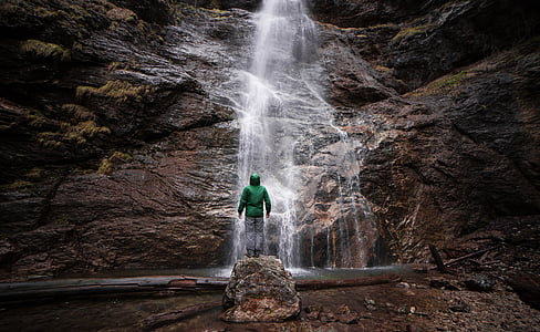 man standing in front of waterfall taken during daytime thumbnail