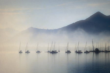 brown boats on lake with fogs near mountain thumbnail