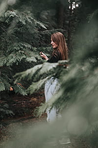 brown haired woman taking a photo of green tres thumbnail